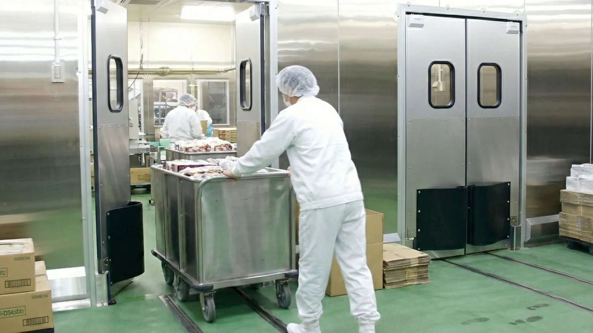 Pintu swing door dengan karyawan sedang melewatinya dengan membawa bahan makanan