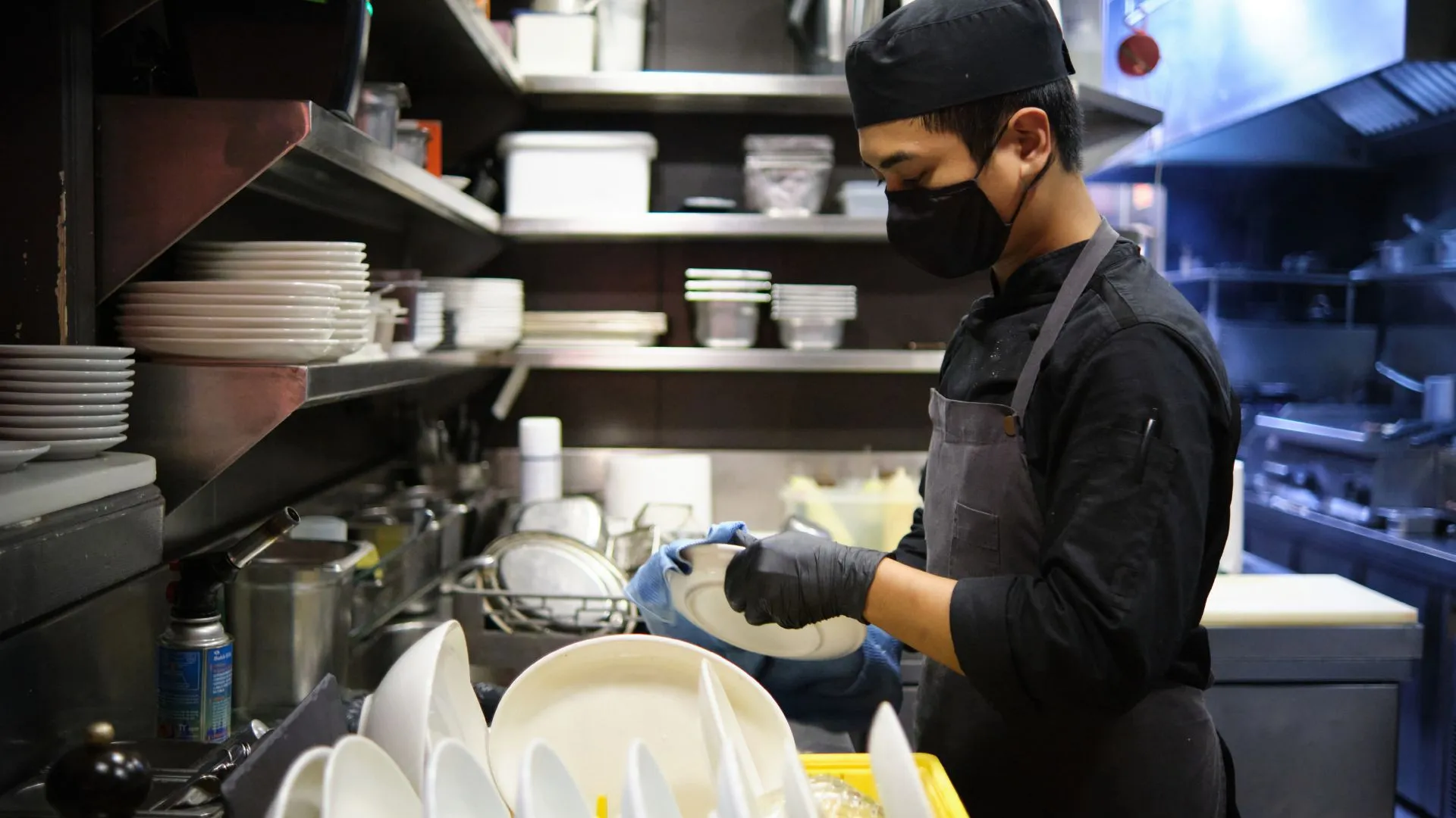 staff dapur mengenakan sarung tangan sedang membersihkan utensil